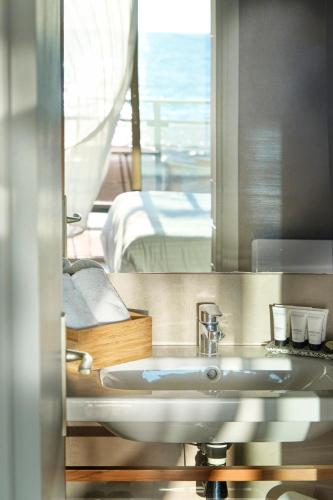 a bathroom with a sink and a bed and a mirror at Hotel Plein Large in Bandol