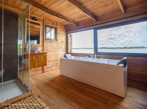 a bathroom with a large tub and a window at LE VILLAGE D'HÉLÈNE - Natura Resort in Ouidah
