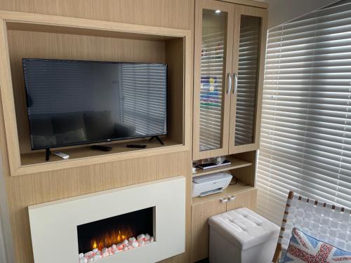 a living room with a tv and a fireplace at Rockley Park Private Holiday Homes in Poole