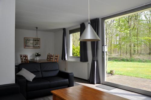 een woonkamer met een bank en een raam bij Vakantiepark Bosmeer Friesland in Noordwolde