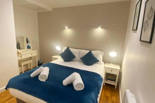 a bedroom with a blue and white bed with towels on it at Modern Serviced 1 Bed Apartment - Sleeps 3 Near Heathrow, Thorpe Park, Windsor Castle - Staines TW18 London in Staines upon Thames