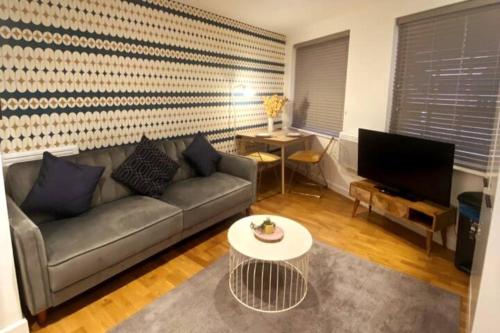 a living room with a couch and a tv at Modern Serviced 1 Bed Apartment - Sleeps 3 Near Heathrow, Thorpe Park, Windsor Castle - Staines TW18 London in Staines upon Thames