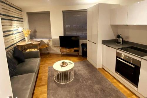 a living room with a couch and a table at Modern Serviced 1 Bed Apartment - Sleeps 3 Near Heathrow, Thorpe Park, Windsor Castle - Staines TW18 London in Staines upon Thames