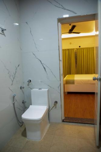 a bathroom with a toilet and a bed in a room at PVR Suites off Bannerghatta Road in Bengaluru