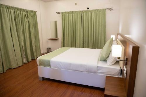 a bedroom with a large bed with green curtains at PVR Suites off Bannerghatta Road in Bengaluru