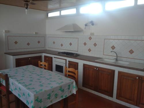 a kitchen with a table and a sink and a stove at B&B vacanze Mille Colori in Cinisi