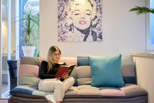 a woman sitting on a couch reading a book at Luna Rossa by Homie in Funchal