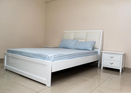 a white bed with a blue pillow and a nightstand at Casa Chico Rosa in Luanda