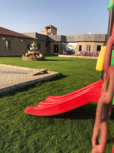 a red slide sitting on the grass in a yard at شاليهات هابي لاند in Ḩalaqat al ‘Afraj