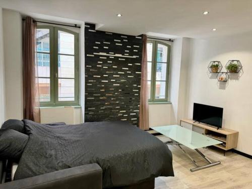 une chambre avec un lit, une table et une télévision dans l'établissement L'escapade Toulonnaise, à Toulon