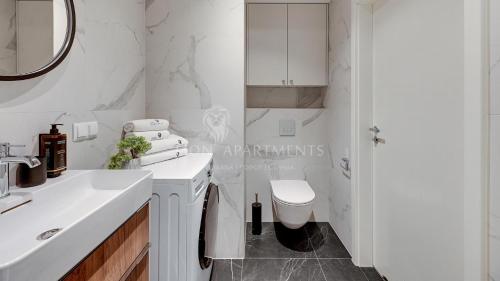 a white bathroom with a sink and a toilet at Lion Apartments - SCALA City Center Apartments&Parking H in Gdańsk