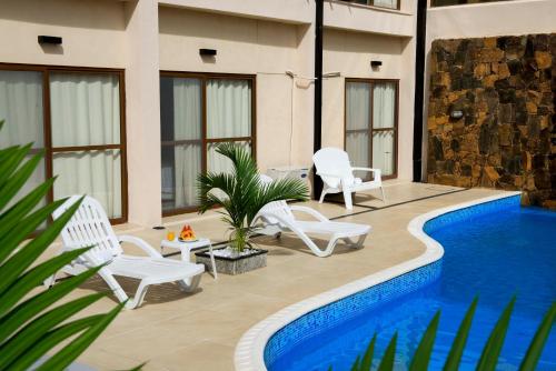 a patio with white chairs and a swimming pool at ARAMI HOTEL & LODGE in Puerto Iguazú