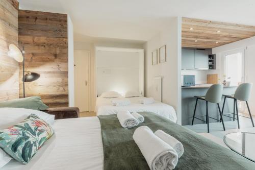 - une chambre avec deux lits et une cuisine en arrière-plan dans l'établissement Magnifique appartement proche du centre, à Crans-Montana