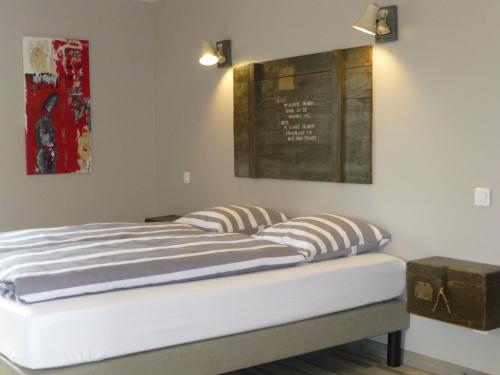 a bed in a room with two pictures on the wall at L’Été en Novembre in Kirrwiller