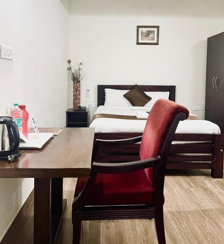 a bedroom with a bed and a wooden table with a red chair at Hotel Coffee Bean in Bengaluru