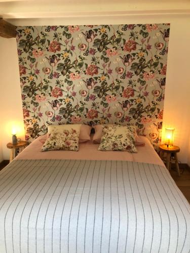 - une chambre avec un grand lit et du papier peint floral dans l'établissement la petite Normande, à Triqueville