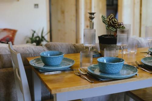 a wooden table with blue bowls and plates on it at Tempo Manor Cabins in Tempo