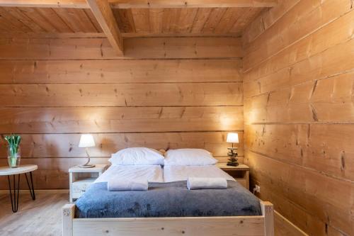 a bedroom with wooden walls and a bed with pillows at udanypobyt Dom Garden SPA in Kościelisko