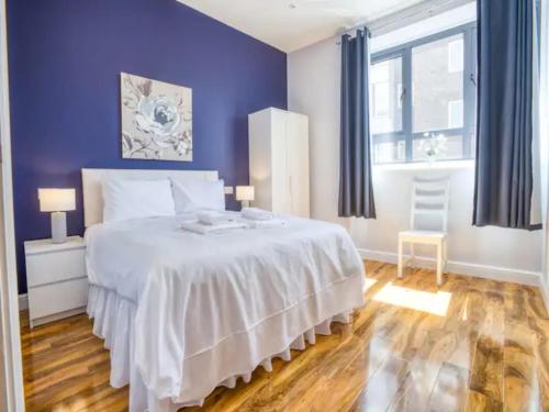 - une chambre avec un grand lit blanc aux murs violets dans l'établissement Pass the Keys Central Apartment with king bed, à Lincoln