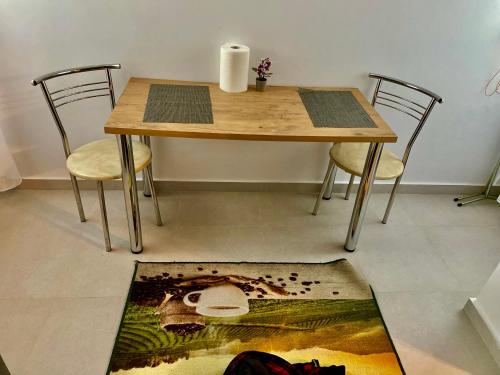 uma mesa de madeira com cadeiras e um tapete no chão em Garsonieră Trivale City em Piteşti