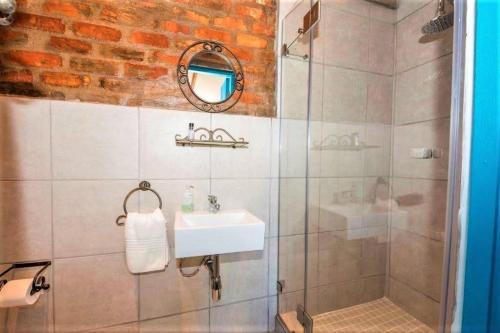 uma casa de banho com um lavatório e um chuveiro com um espelho. em Wine Route Cottages em Simondium