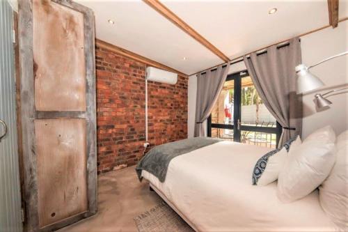 a bedroom with a large bed and a brick wall at Wine Route Cottages in Simondium