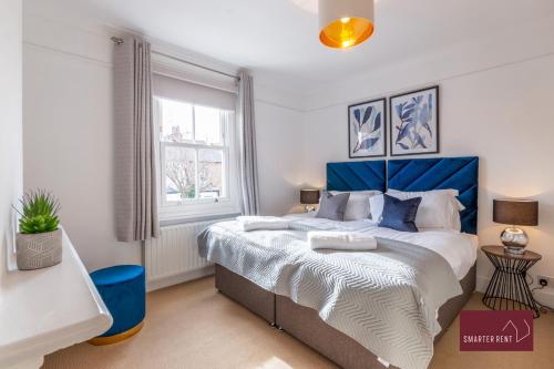 a bedroom with a large bed with a blue headboard at 3 Bed Victorian House - Kingston On Thames in Kingston upon Thames