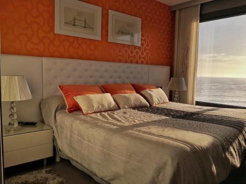 a bedroom with a bed with orange walls and a window at Luxury centro Silgar in Sanxenxo