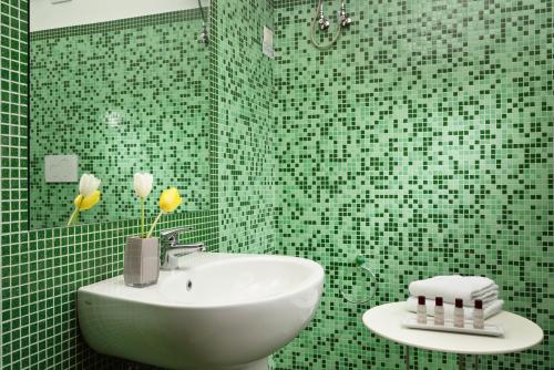 a green tiled bathroom with a sink and a mirror at Hotel Recostano Residence in Trevignano Romano