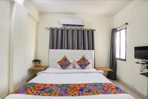 1 dormitorio con 1 cama con una manta colorida en FabExpress Osca Inn, en Nagpur