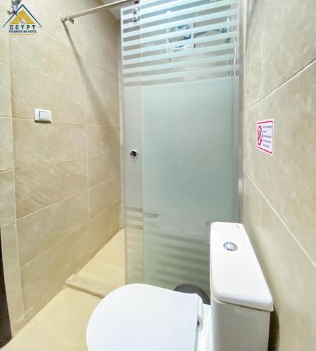 a bathroom with a white toilet and a shower at Egypt Pyramids Inn in Cairo