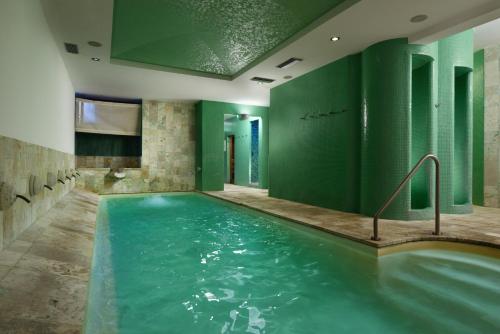 a pool in a room with green walls at Hotel Recostano Residence in Trevignano Romano