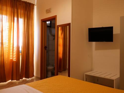 1 dormitorio con 1 cama y TV en la pared en Villa Flora, en Pompeya