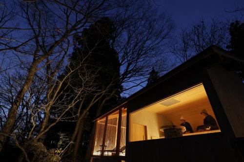two people sitting on the window of a house at night at Satoyama Jujo The House in Minami Uonuma