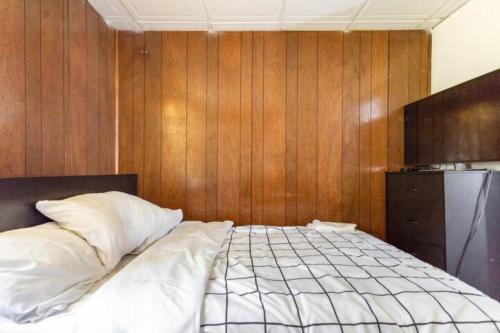 a bedroom with a bed with wooden walls and a refrigerator at room with a private shower in Arlington