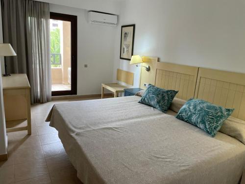ein Schlafzimmer mit einem großen Bett mit blauen Kissen in der Unterkunft Vista jardín en Urb. Jardines de Isla Canela. in Ayamonte