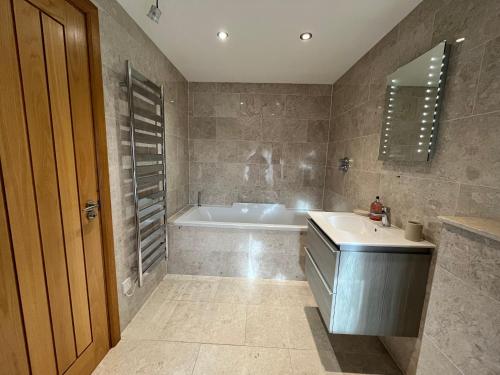 y baño con bañera, lavamanos y bañera. en Shircombe Lodge - Exmoor National Park, en Dulverton