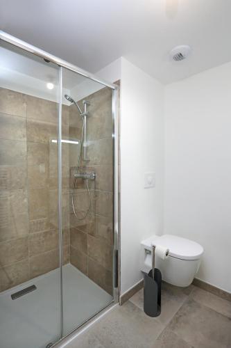 une salle de bain avec une douche en verre et des toilettes dans l'établissement Citadella confort moderne au centre de Calvi, à Calvi