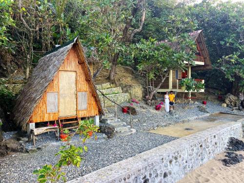 a small house with people standing outside of it at L'Astrolabe - Private Beach in Baras