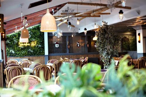 uma sala de jantar com mesas, cadeiras e plantas em Highfield Hotel em Houghton le Spring