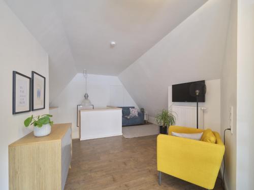 a living room with a yellow chair and a tv at Hof Maiholm - Heuboden in Medelby