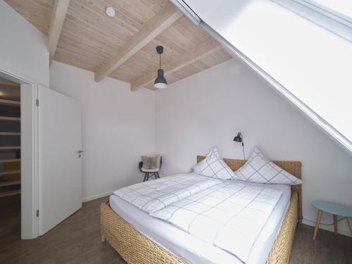 a bedroom with a bed with white sheets and a wooden ceiling at Hof Maiholm - Heuboden in Medelby