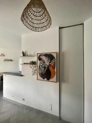 Cette chambre est dotée d'un mur blanc avec un lustre. dans l'établissement Charmant T2 à 500 m des plages, à Vallauris