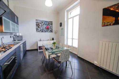 una cocina con mesa de cristal y sillas. en Appartamento Casa Nizza - Metro Lingotto fiere by Bib's Apartments, en Turín