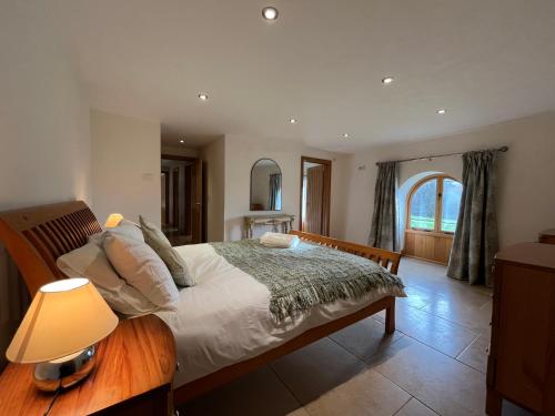 1 dormitorio con 1 cama con lámpara y espejo en Shircombe Lodge - Exmoor National Park, en Dulverton