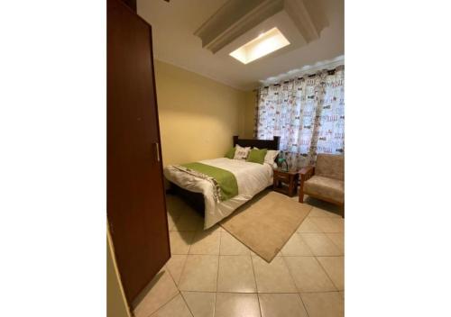 een slaapkamer met een bed, een bank en een raam bij 3 Bedroom In Riara RH67 in Nairobi