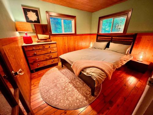a bedroom with a bed and a dresser and windows at Vintage Downtown Cabin in Squamish