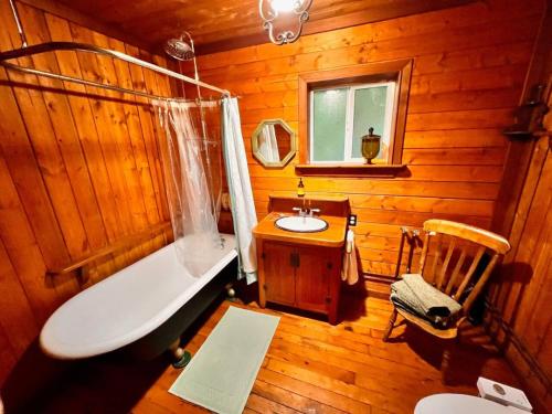 a wooden bathroom with a tub and a sink at Vintage Downtown Cabin in Squamish