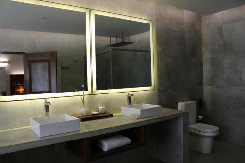 uma casa de banho com 2 lavatórios e um espelho em Trinco Boutique Hotel em Triquinimale