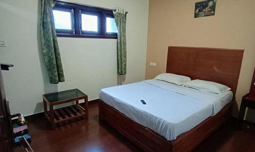 um quarto com uma cama e uma janela em FabHotel Sri Guhan EIite em Kodaikānāl